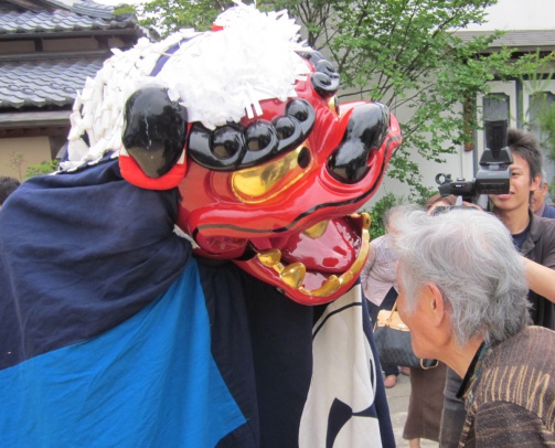 施設のイベントで入居者が大きな獅子舞のオブジェと触れ合っている風景